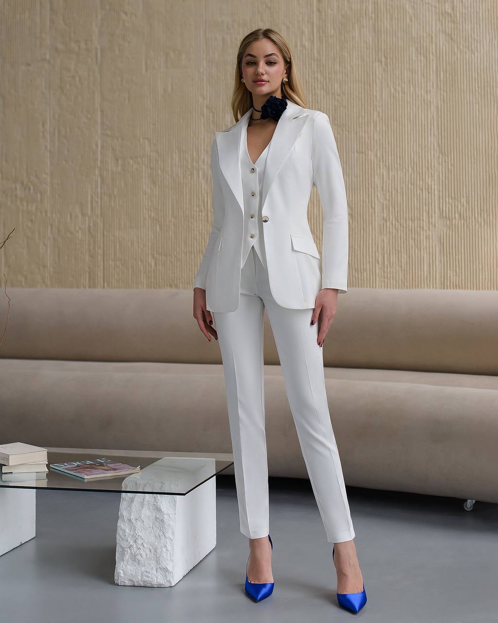 Woman wearing a white suit with blue shoes in a living room setting