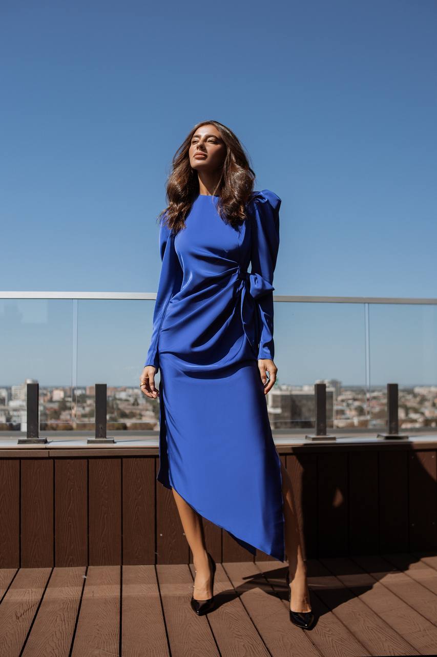 Woman in a blue dress standing on a rooftop with a cityscape in the background