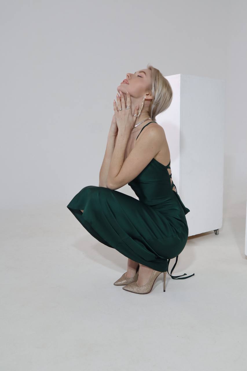 Woman in a green dress sitting on the floor with a white background