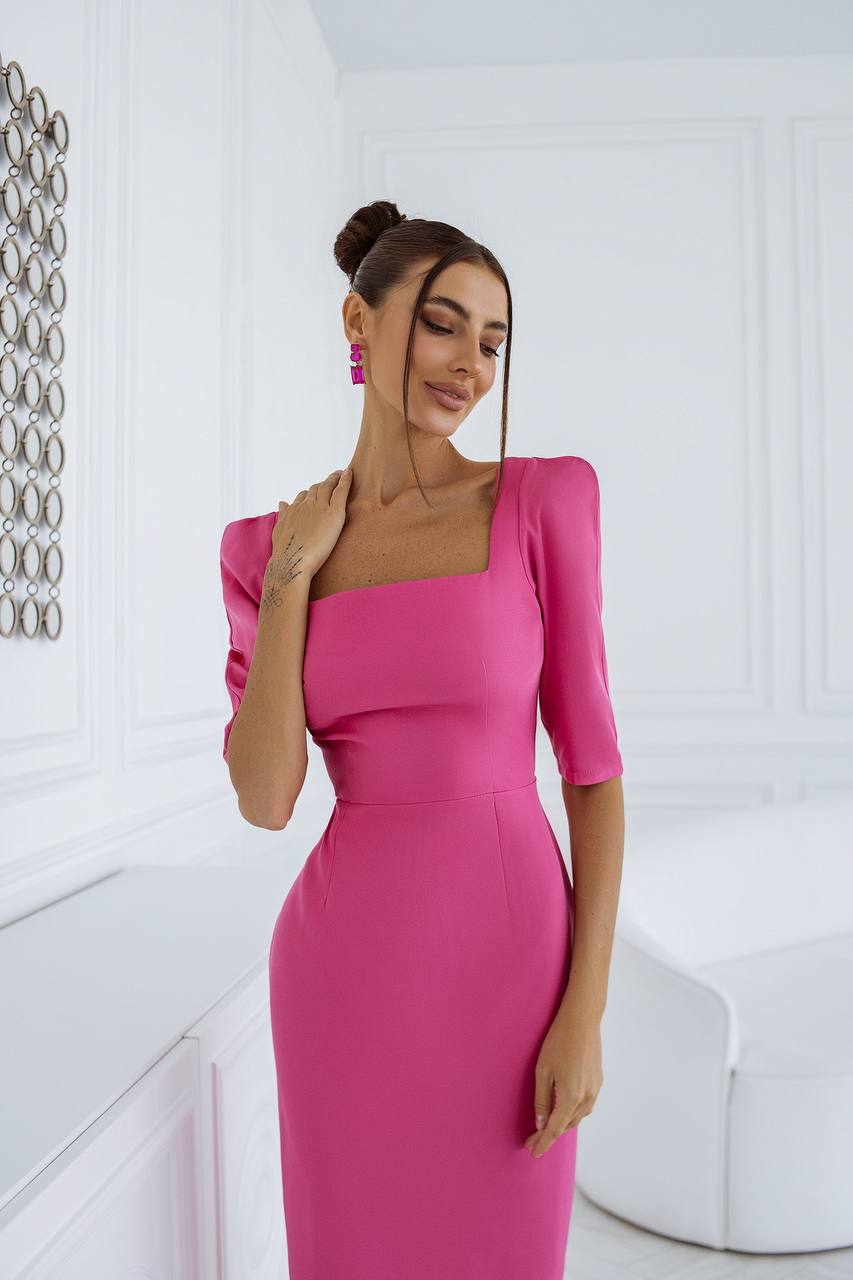 Woman wearing a pink dress in a white room