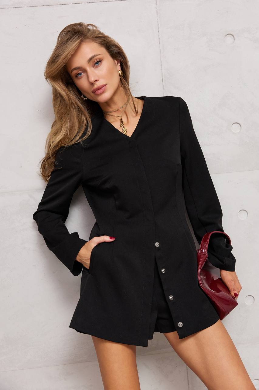 Woman wearing a black outfit with a red handbag against a light gray background