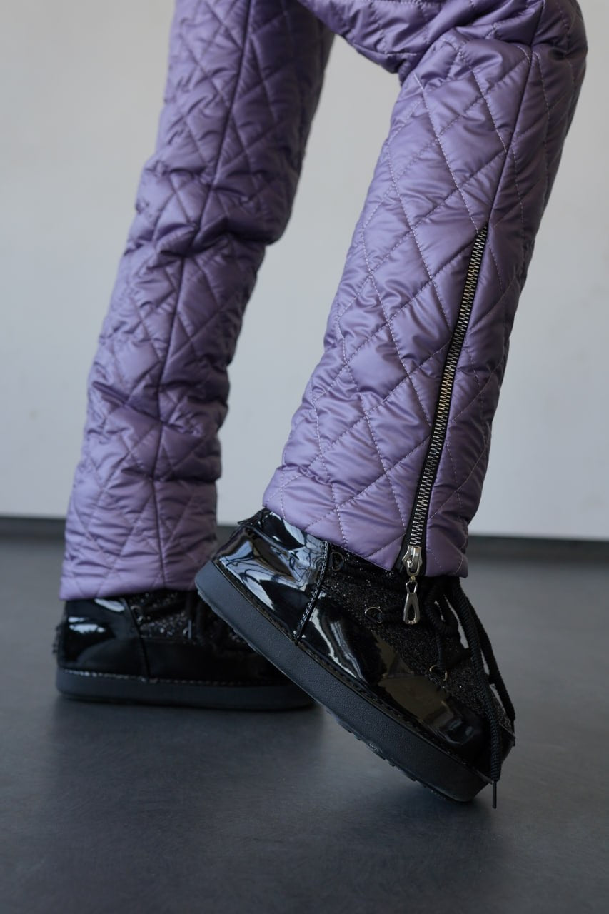 Purple quilted pants and black shoes on a plain background
