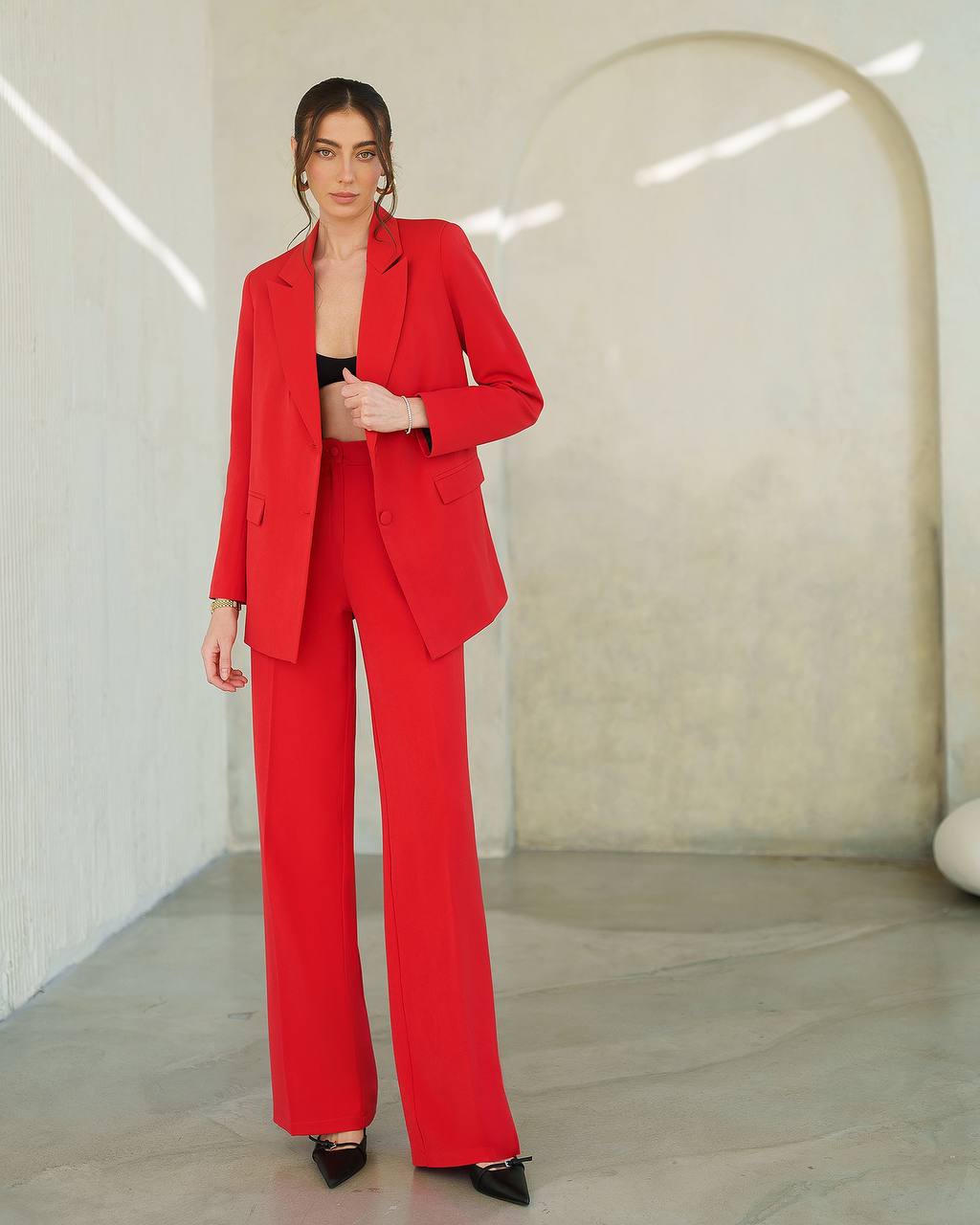 Woman wearing a red suit in a minimalistic setting
