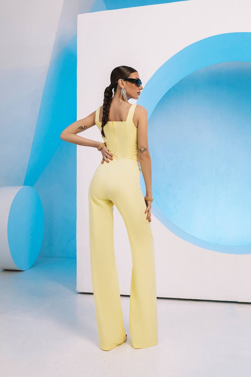 Woman in a yellow jumpsuit standing against a modern, abstract blue and white background