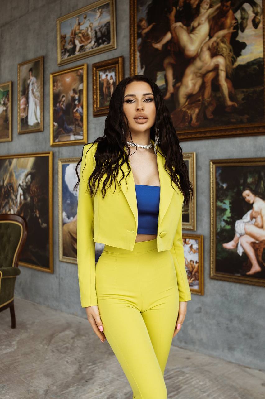 Woman in a yellow suit standing in front of artistic wall decorations