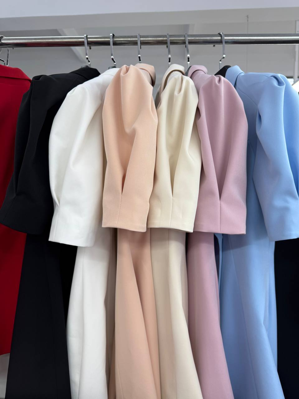Row of colorful blazers hanging on a rack.
