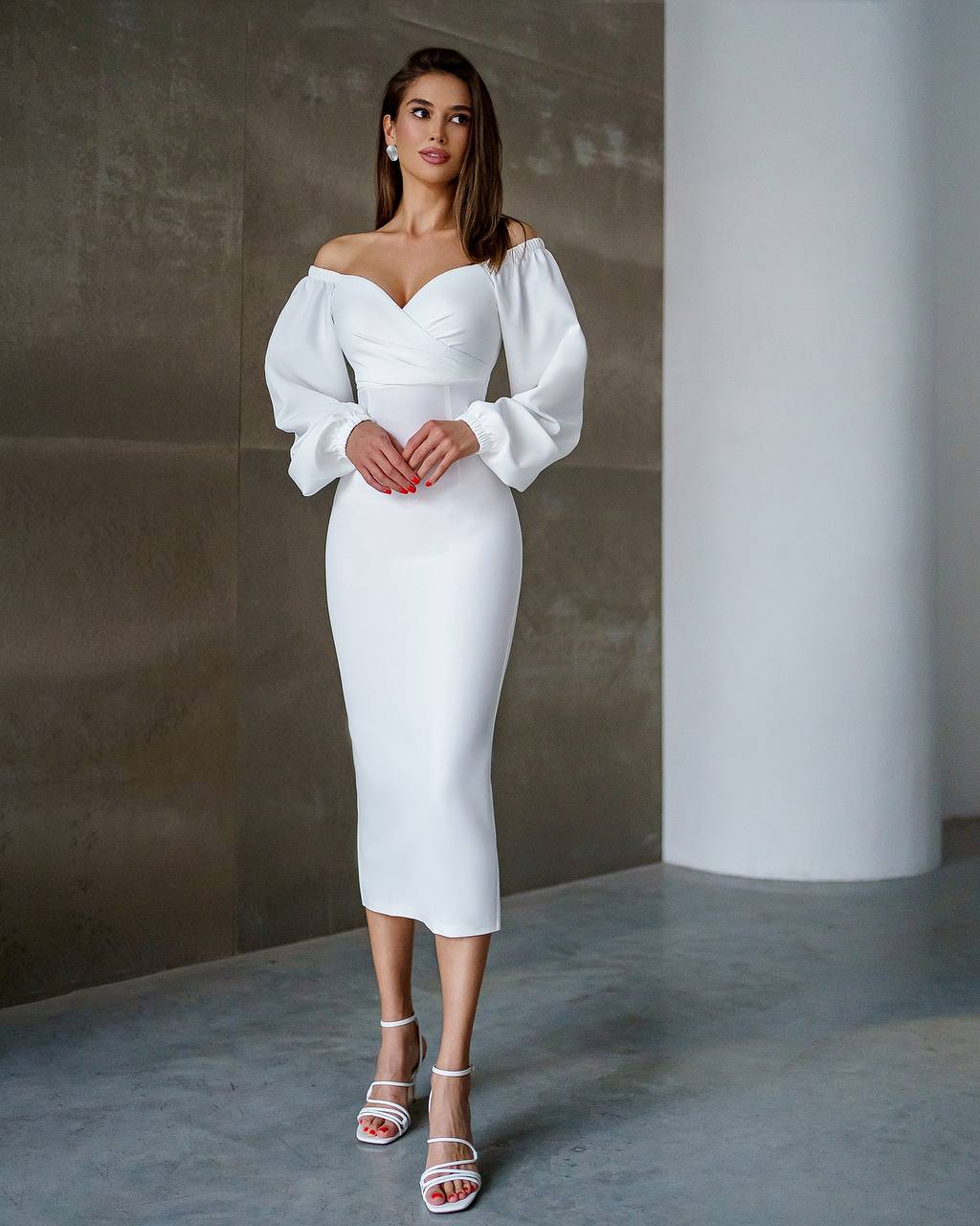 Woman wearing a white off-shoulder dress in a minimalistic setting
