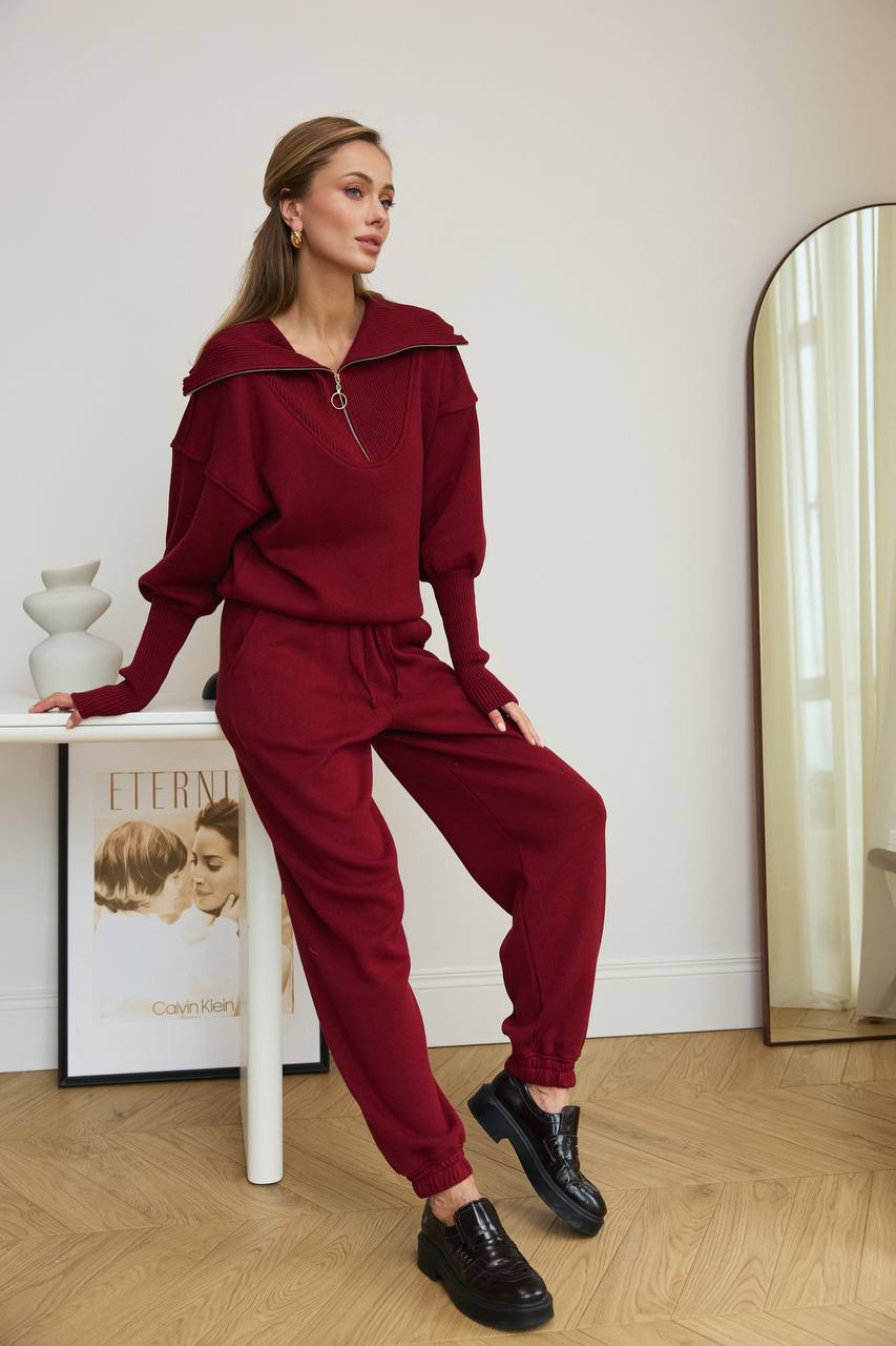 Woman in burgundy outfit posing in a room with a mirror and decor.