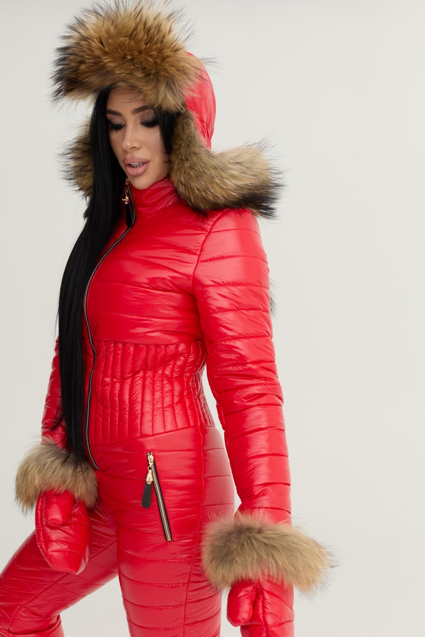 Person wearing a red puffer jumpsuit with fur trim on a white background