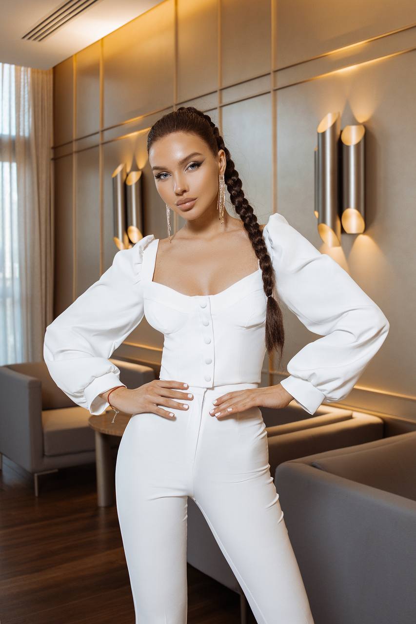 Woman in a white outfit posing in an elegant interior setting