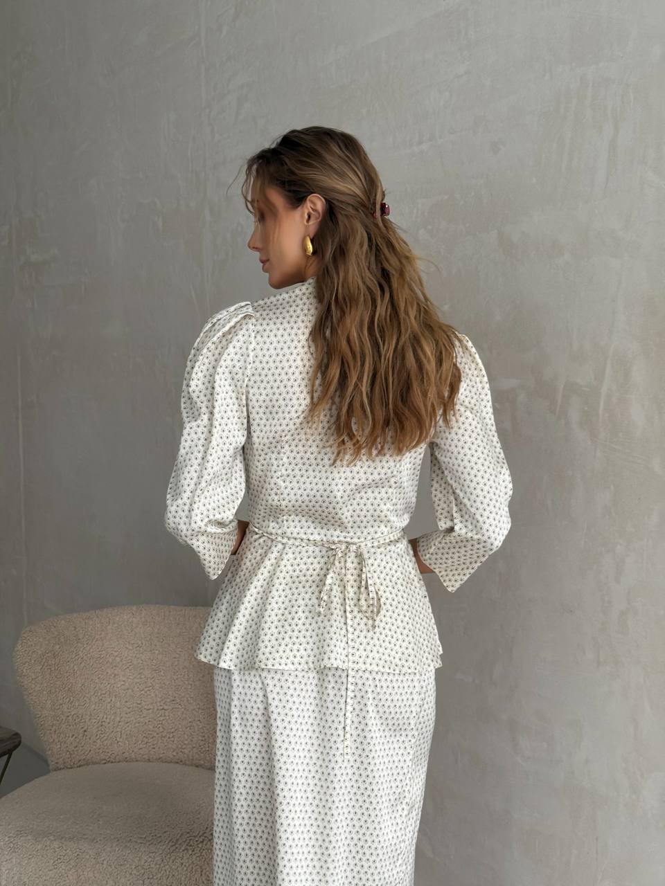 Woman wearing a polka dot outfit against a plain wall