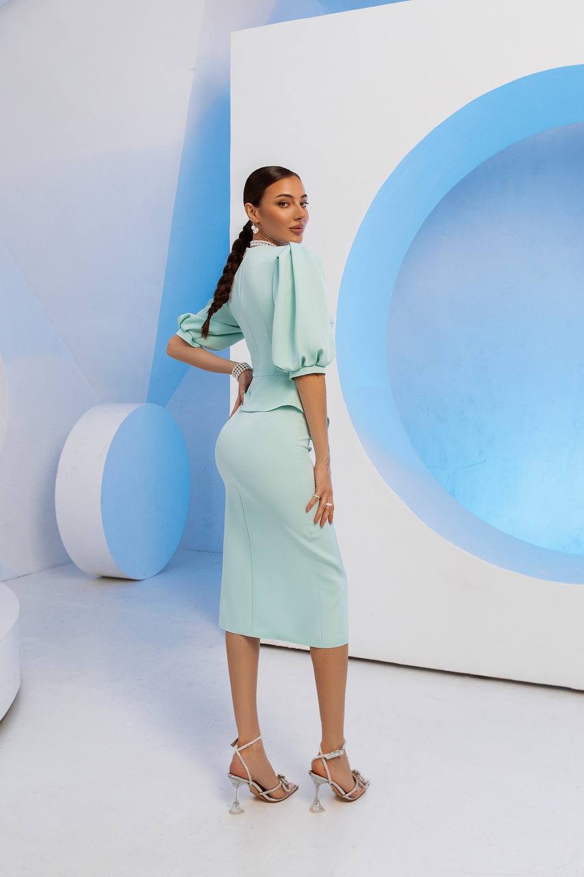 Woman in a light green outfit standing in a modern, minimalistic setting with blue and white colors.