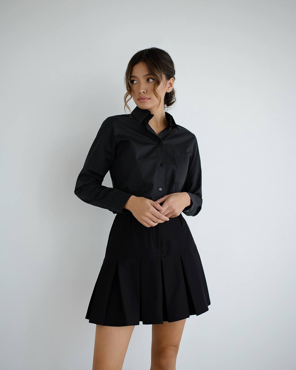 Woman wearing a black dress against a plain background