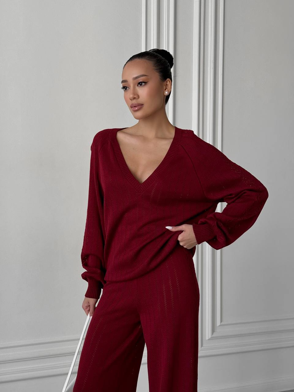 Woman wearing a burgundy outfit against a gray wall