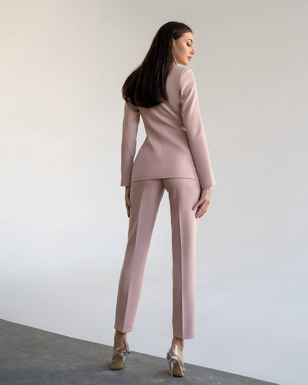 Woman wearing a pink suit standing against a plain white background