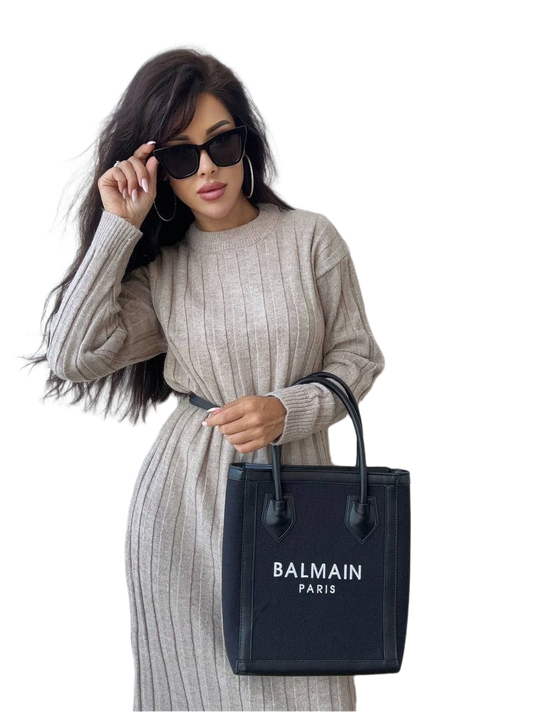 Woman holding a Balmain handbag against a white background