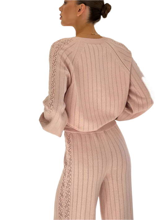 Pink knit outfit with lace details on a white background