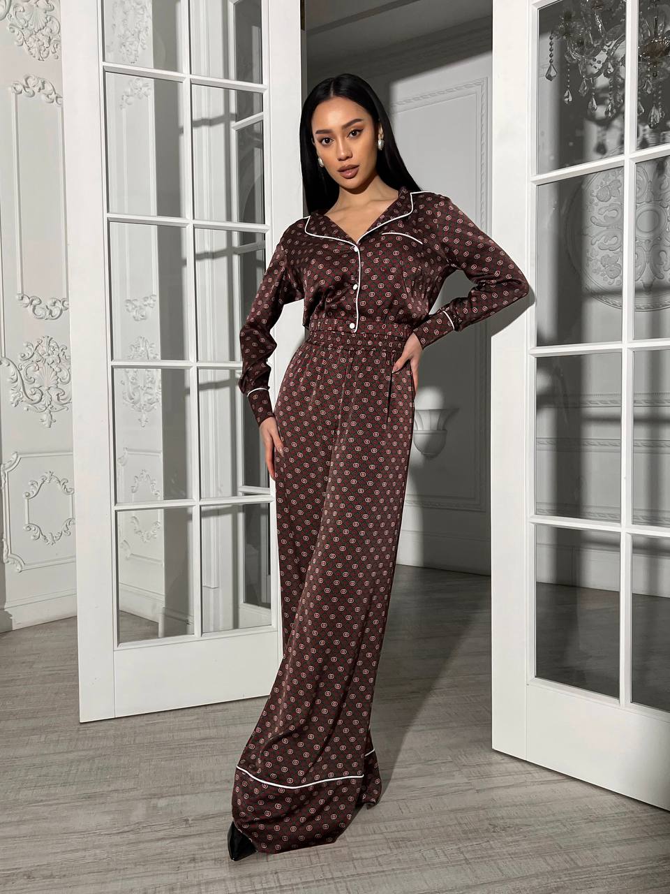 Woman wearing a brown patterned nightgown standing in a doorway.