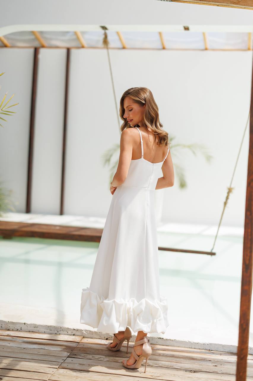 Woman in a white dress standing on a wooden deck with a pool and swing in the background