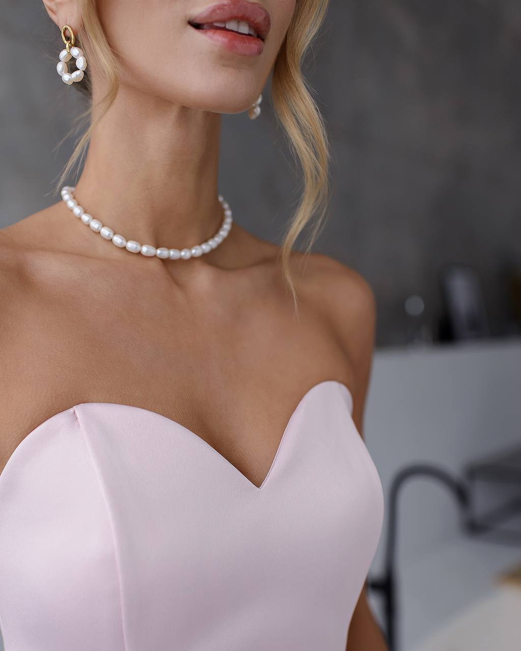 Close-up of a woman wearing a pearl necklace and earrings with a blurred background