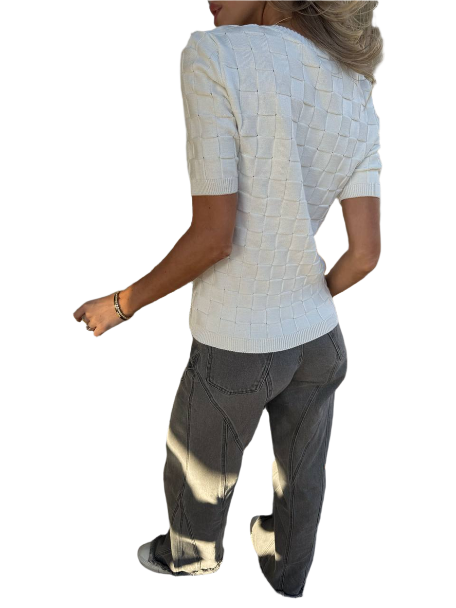 Person wearing a textured white top and dark pants on a white background