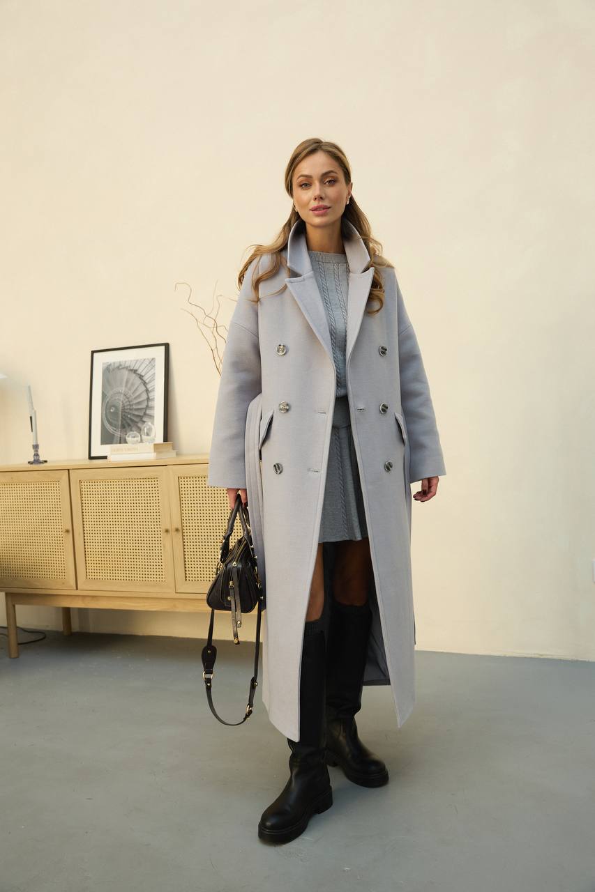 Woman wearing a long gray coat in an indoor setting