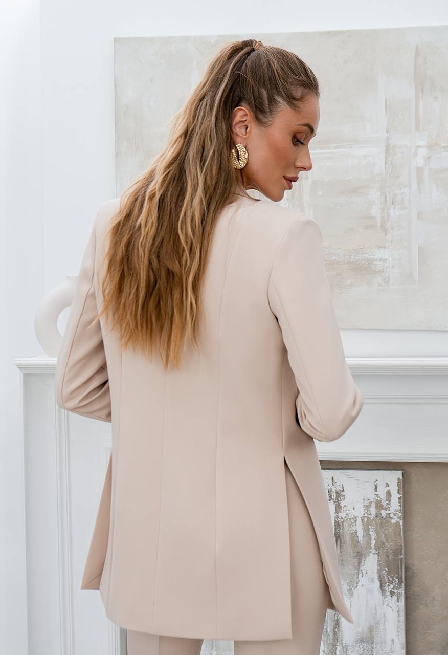 Woman wearing a beige blazer in a neutral setting