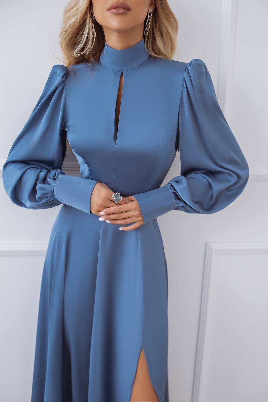 Woman wearing a blue dress with long sleeves against a white background