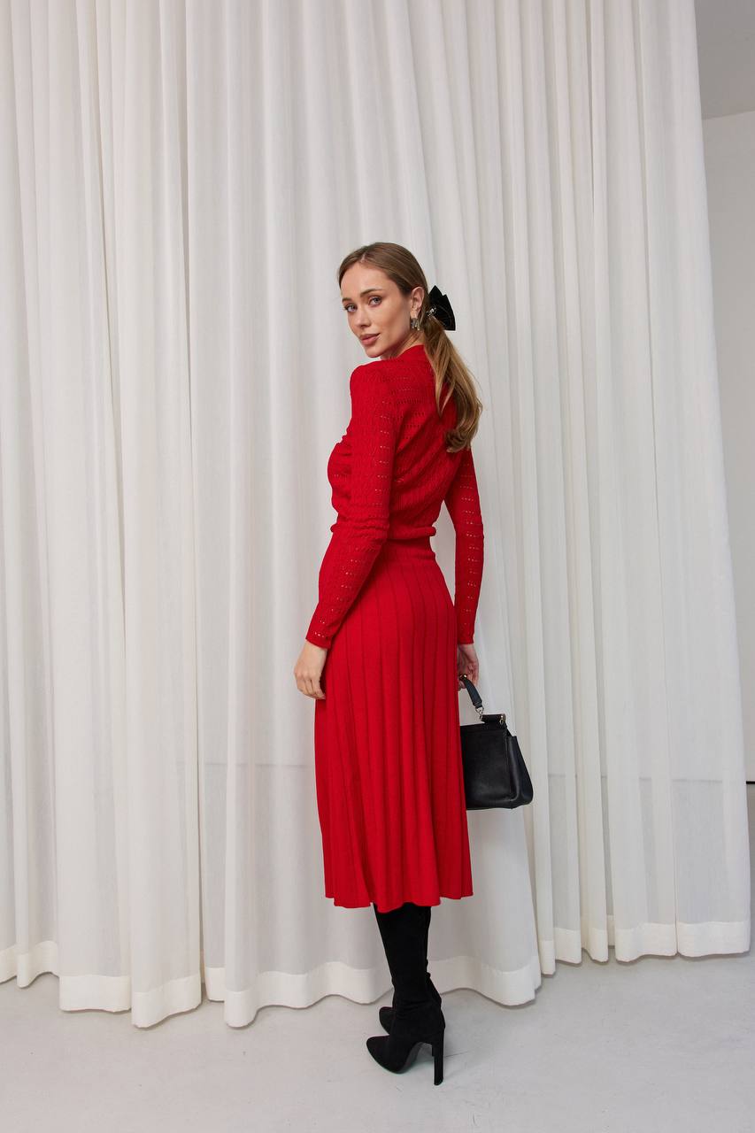 Woman in a red dress standing against a white curtain