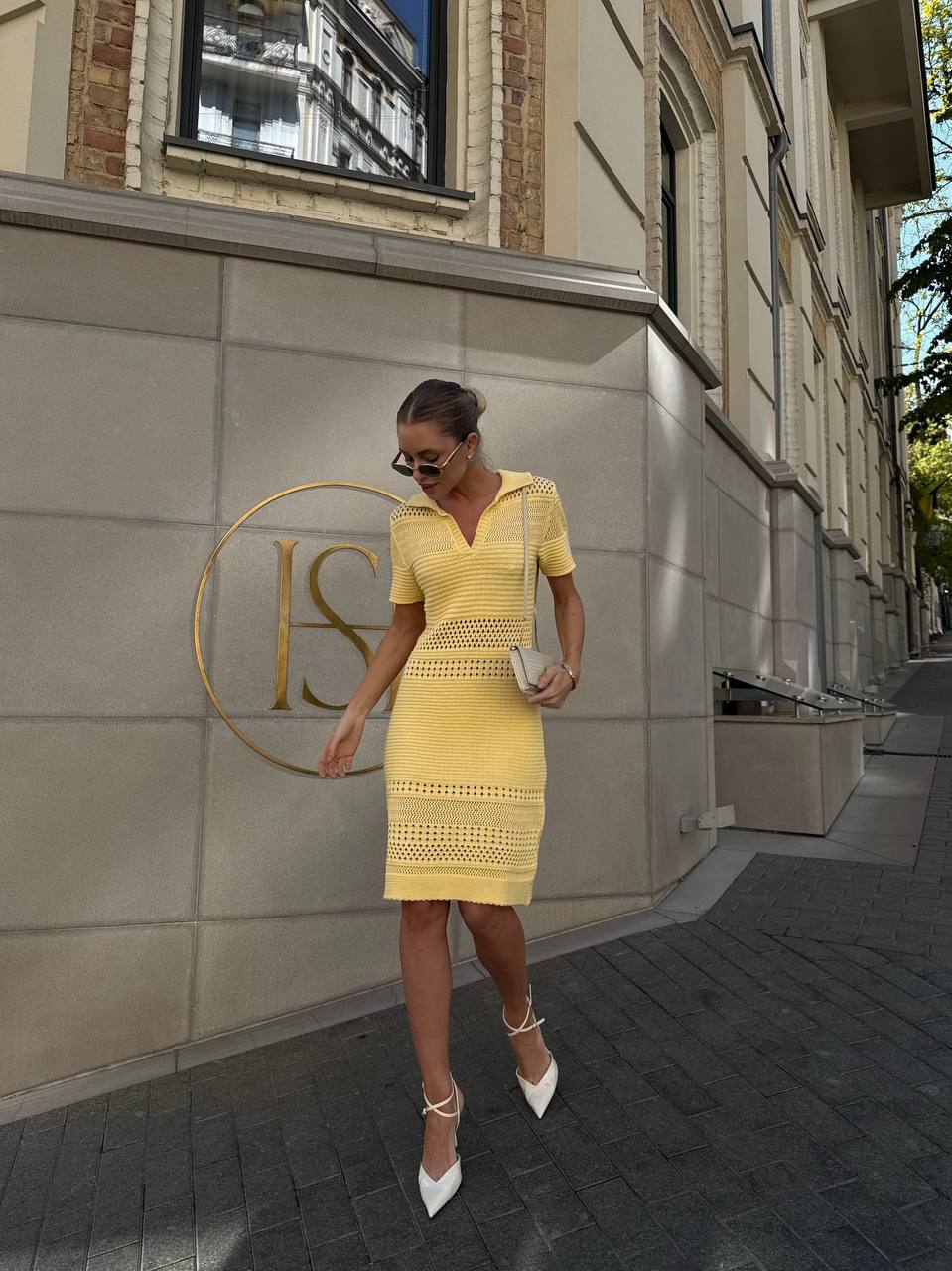 Woman in a yellow dress walking on a street with a building in the background