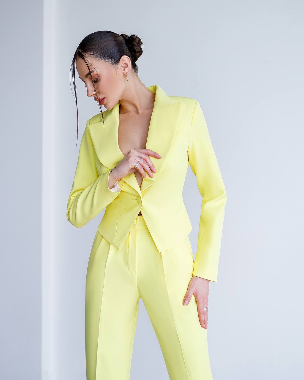 Woman wearing a bright yellow suit against a light gray background