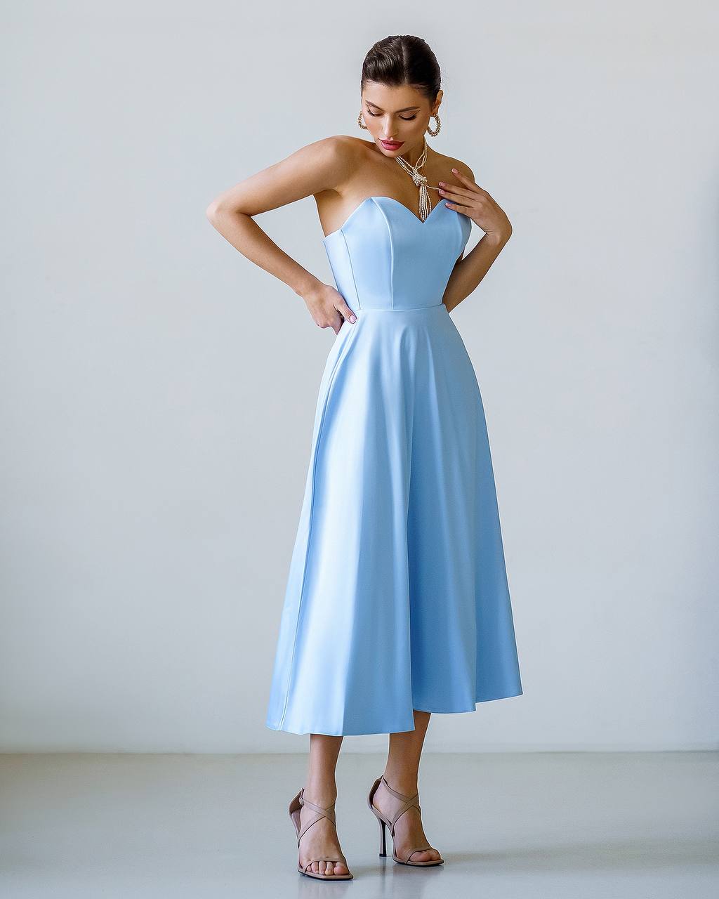 Woman wearing a light blue strapless dress against a white background