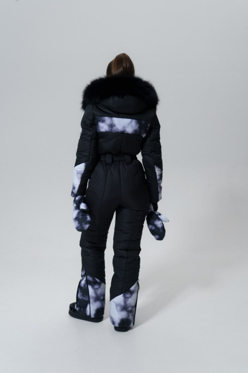 Person wearing a black snowsuit with white pattern on a light gray background