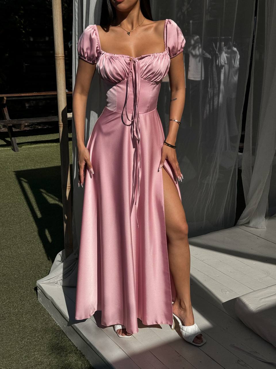 Woman wearing a pink dress with a high slit on a platform.