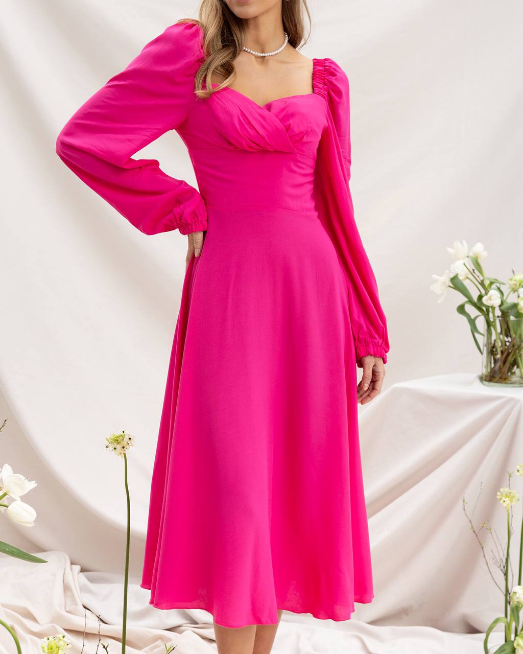 Woman wearing a bright pink dress with long sleeves on a white background