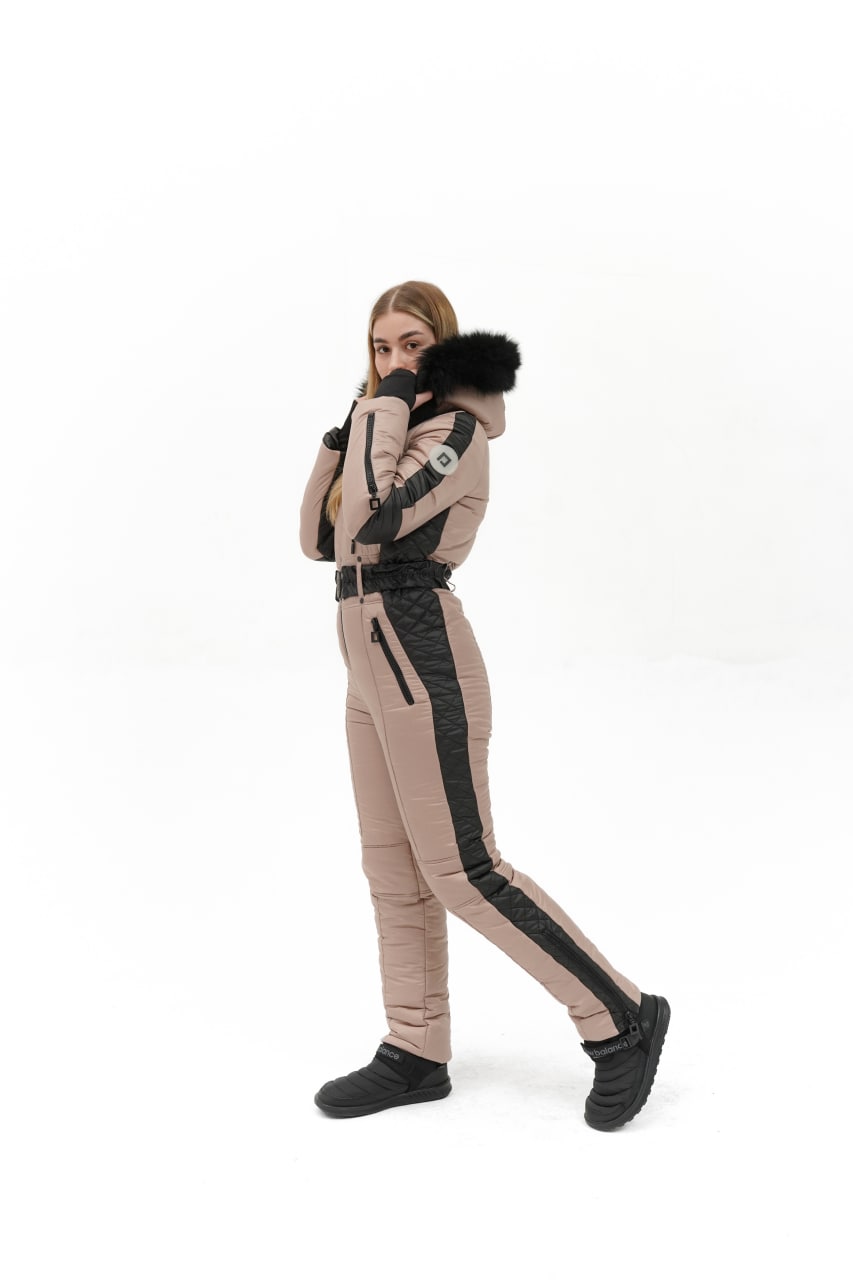 Person wearing a beige and black winter outfit with fur-lined hood on a white background