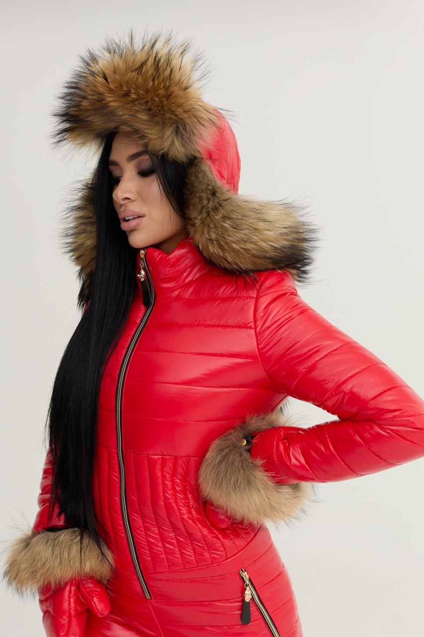 Person wearing a red puffer coat with fur hood and cuffs on a white background