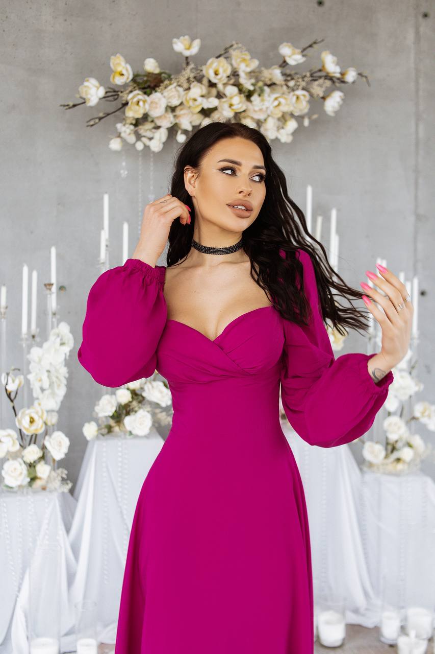 Woman in a pink dress standing in a decorated room with flowers and candles.