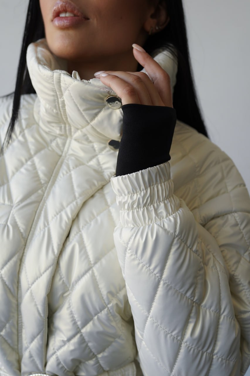 Close-up of a person wearing a white quilted jacket with a neutral background