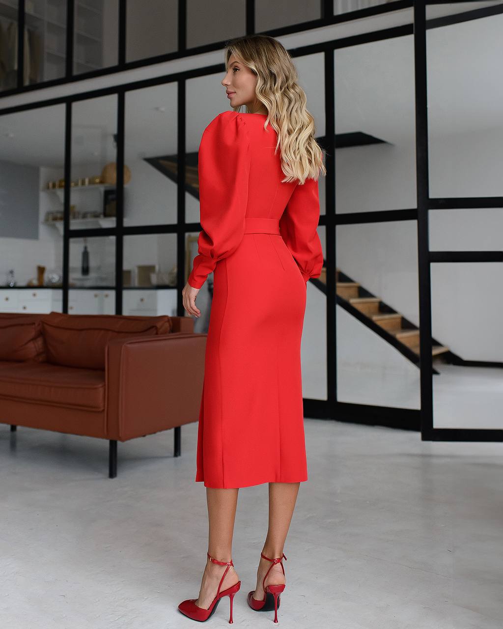 Woman in a red outfit standing in a modern interior setting