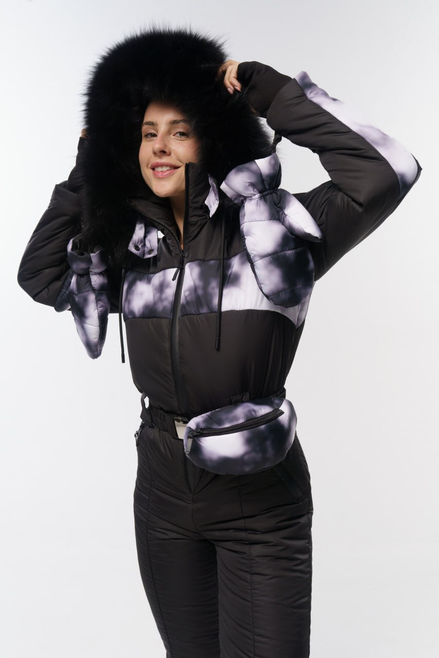 Person wearing a black and white patterned jacket with fur-lined hood on a white background