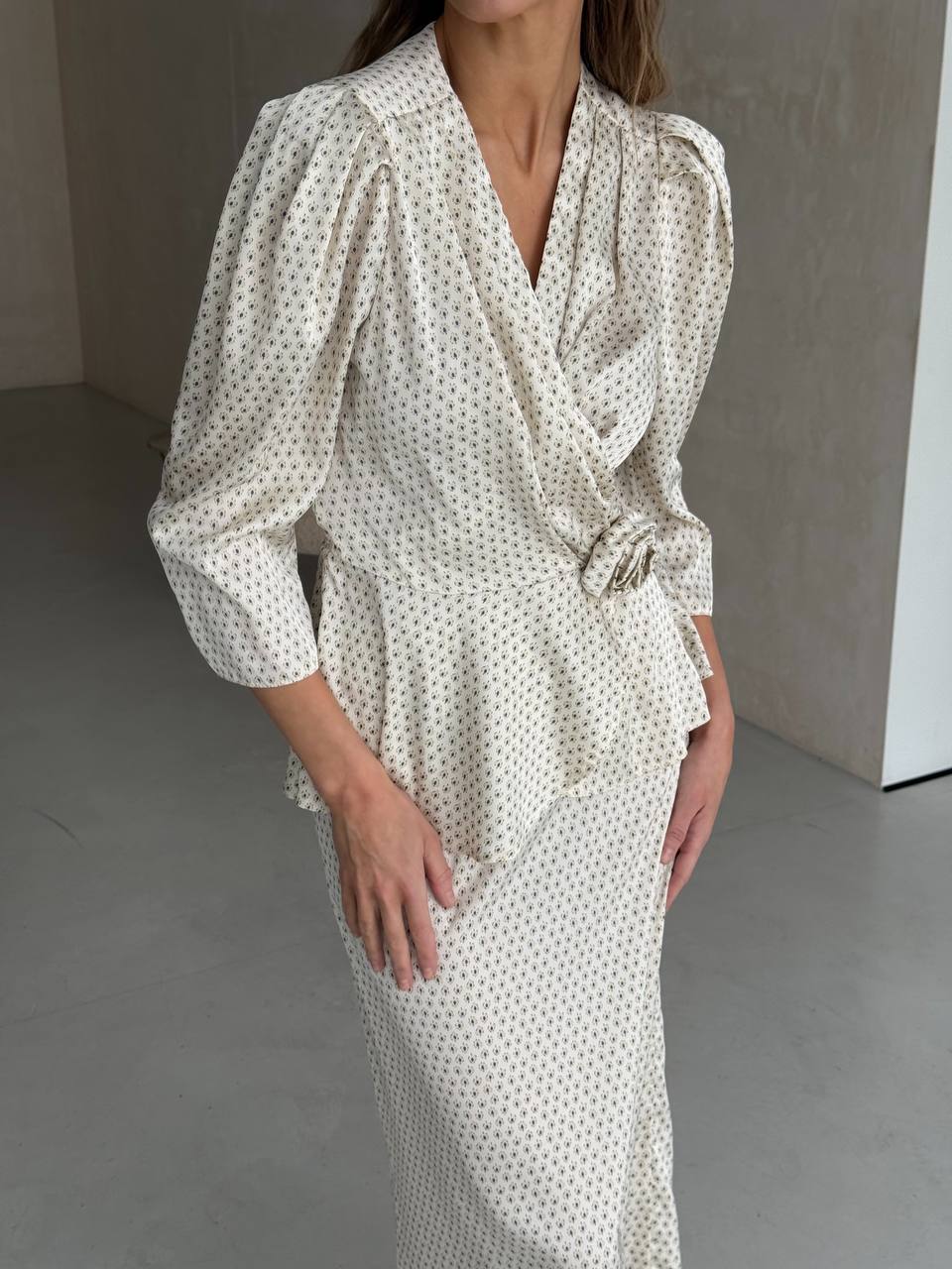 Woman wearing a white dress with black polka dots in a minimalistic setting
