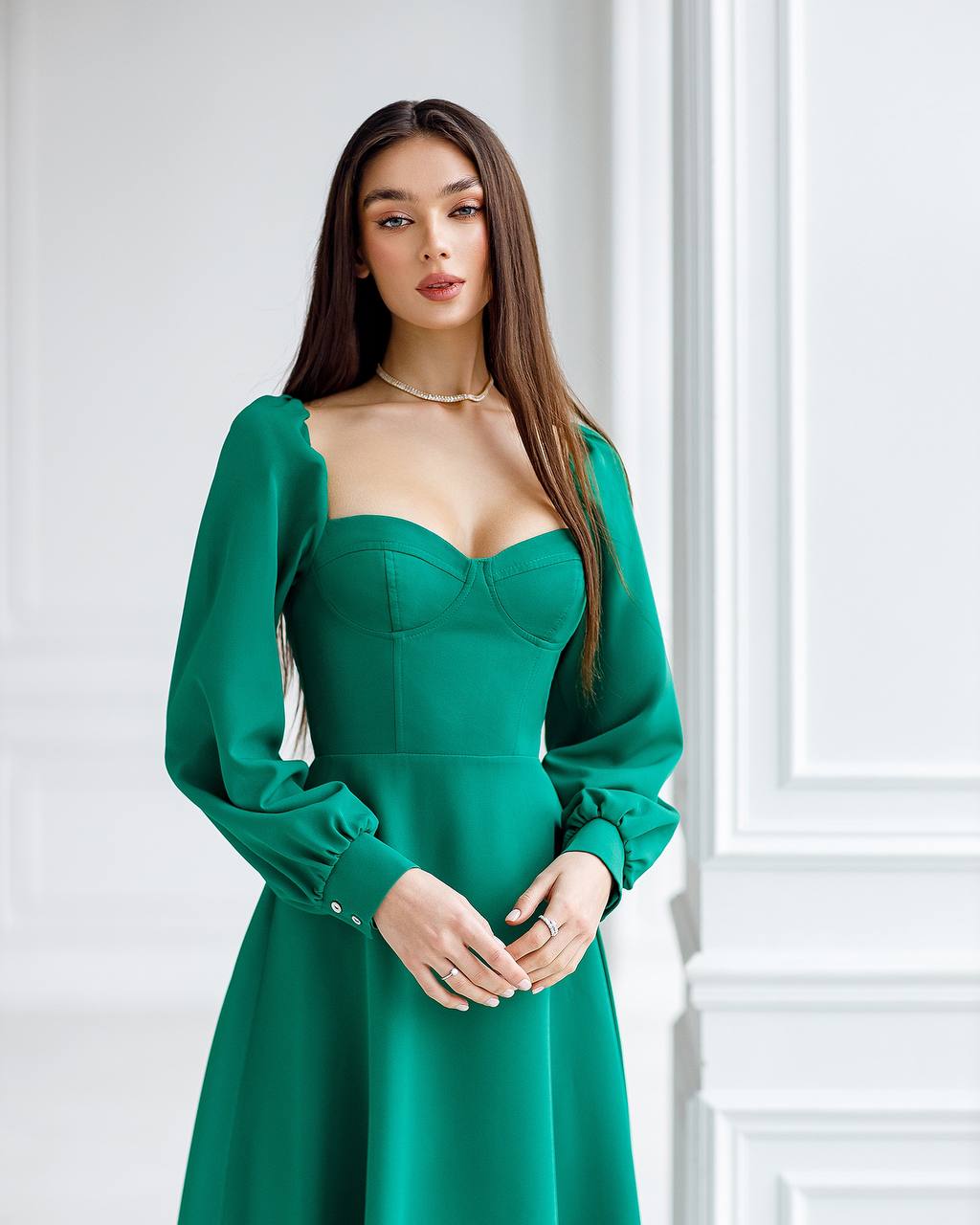 Woman wearing a green dress with long sleeves in an elegant interior setting