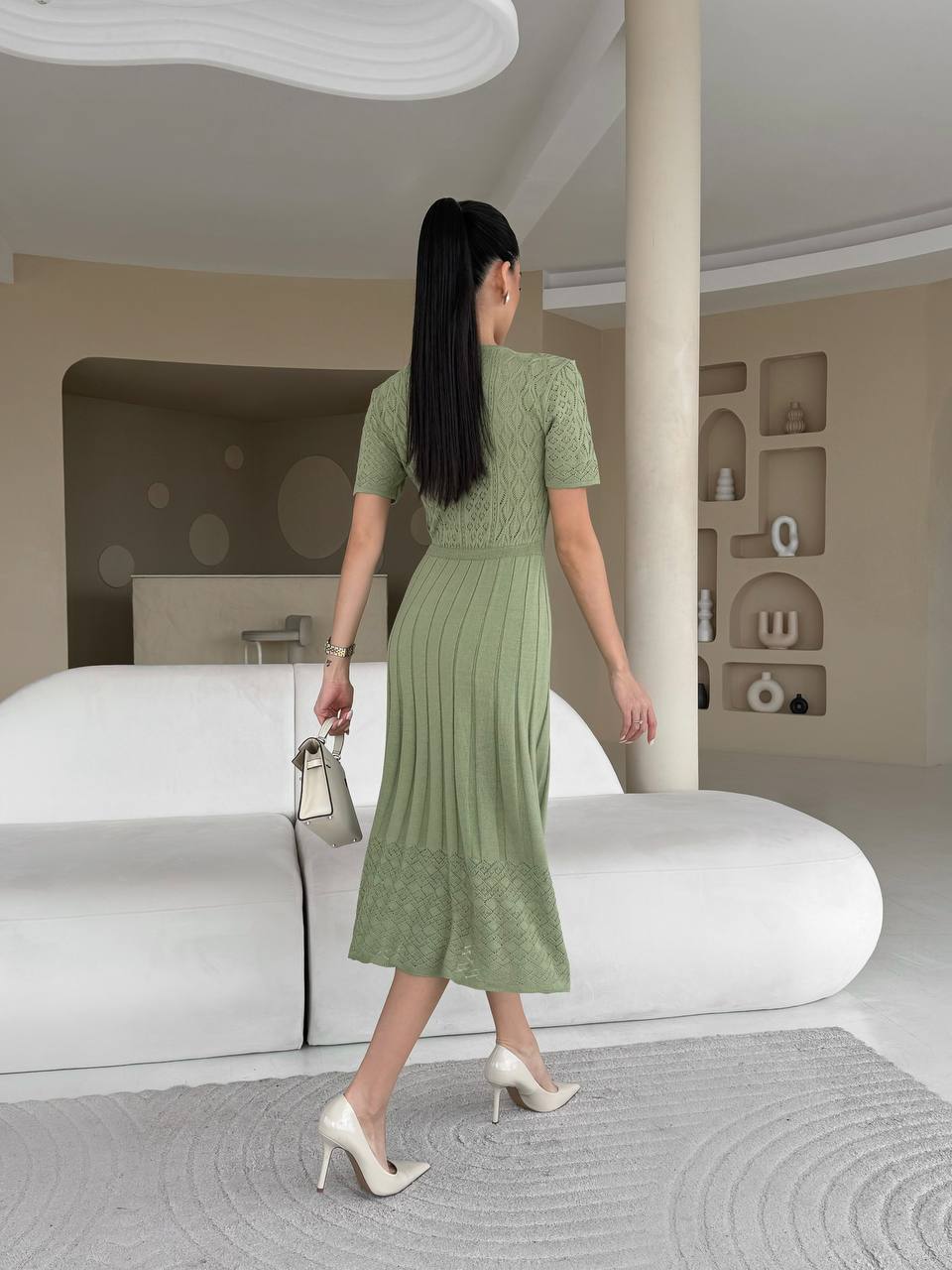 Woman in a green dress walking in a modern interior setting