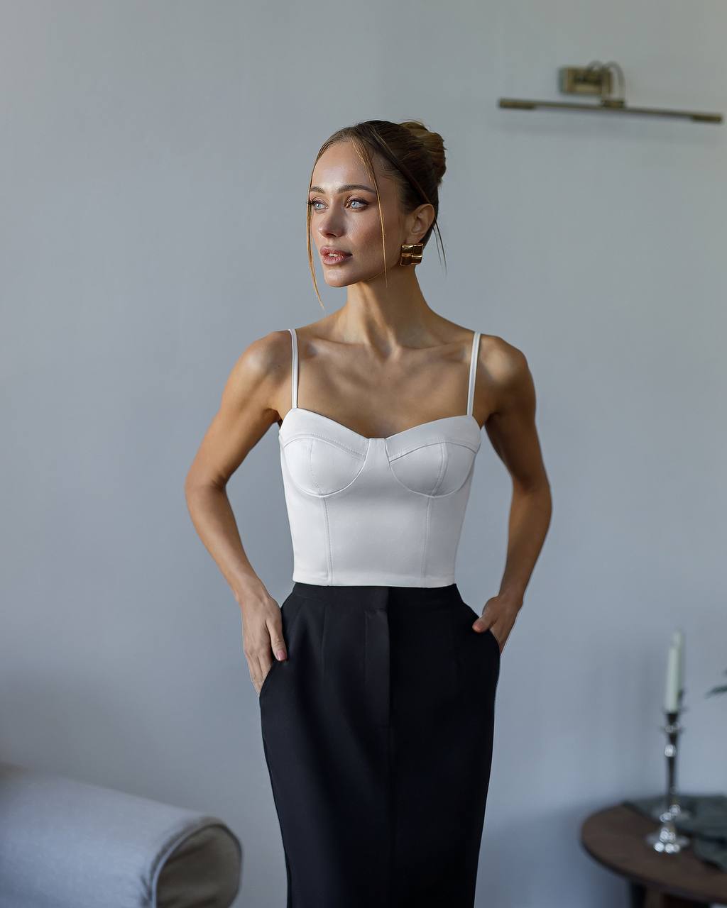 Woman wearing a white bra and black pants against a neutral background
