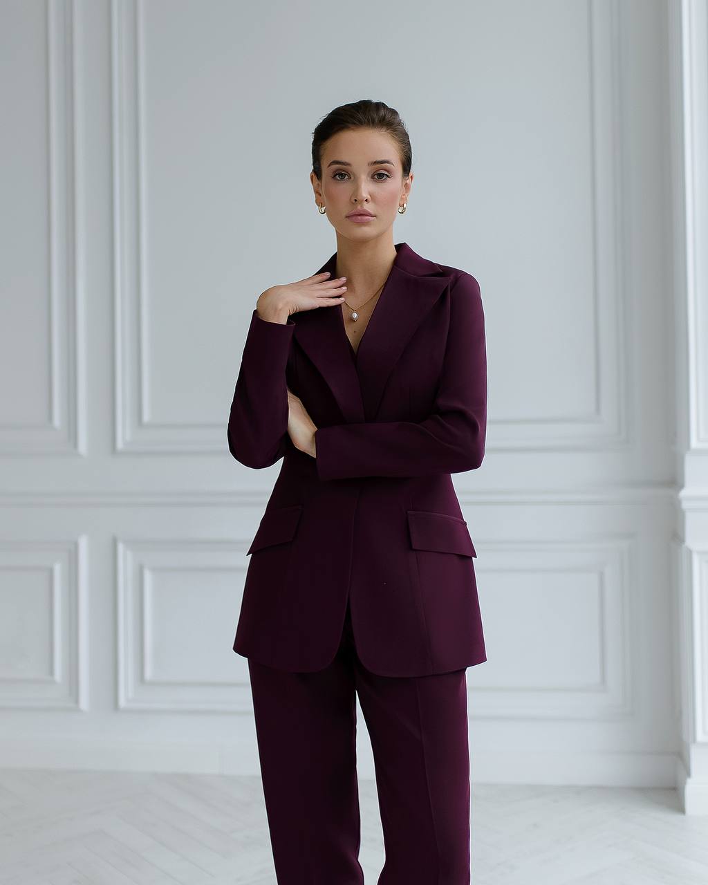 Woman wearing a burgundy suit against a white wall