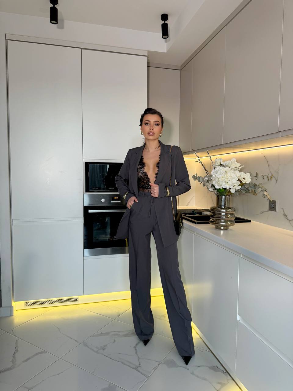Person in a stylish outfit standing in a modern kitchen.