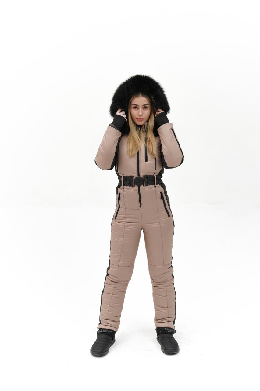 Person wearing a beige snowsuit with black fur hood on a white background