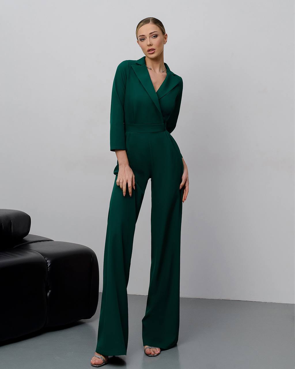Woman wearing a green jumpsuit standing against a plain background