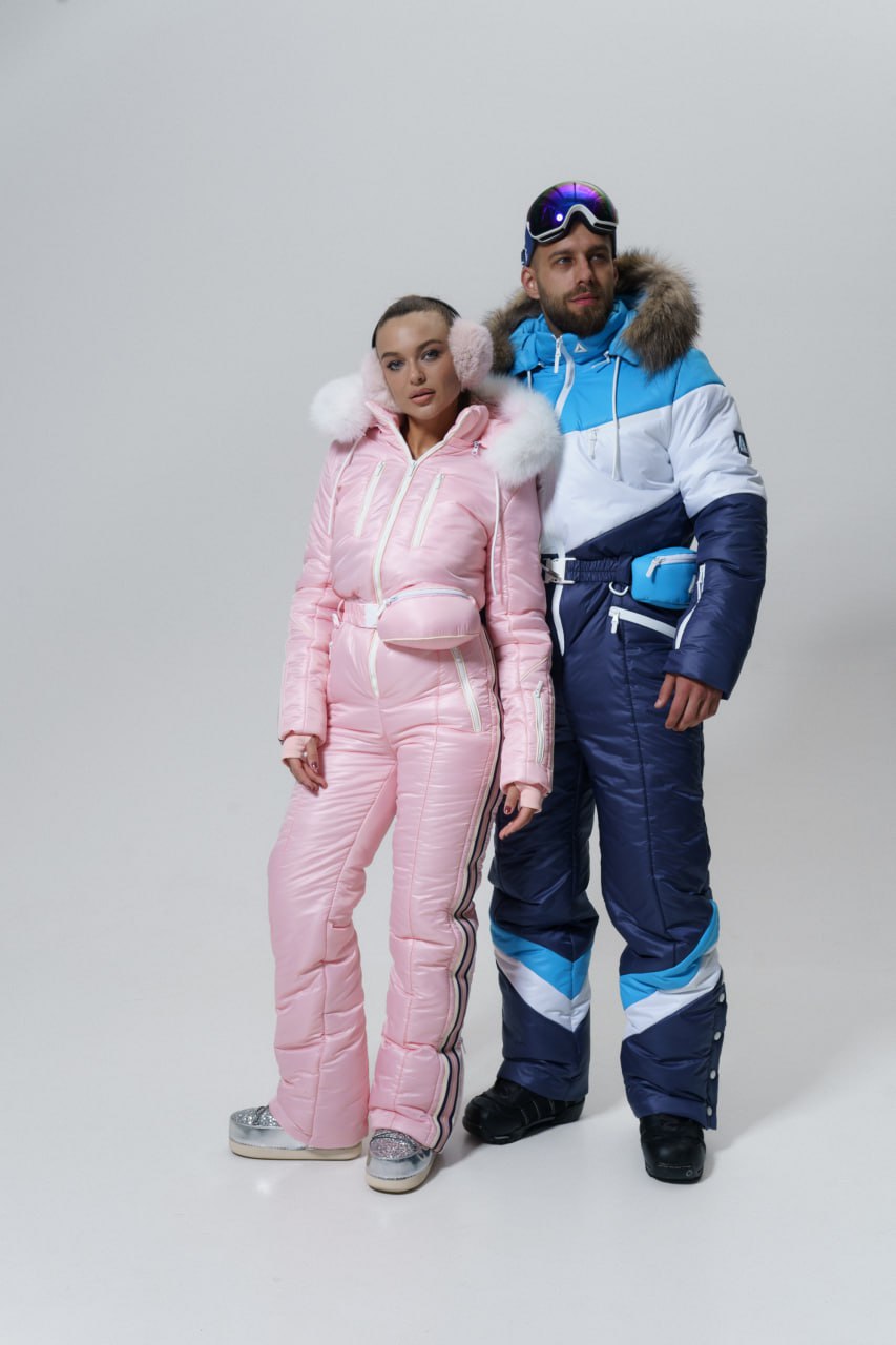 Two people wearing colorful winter outfits with pink and blue snowsuits on a white background